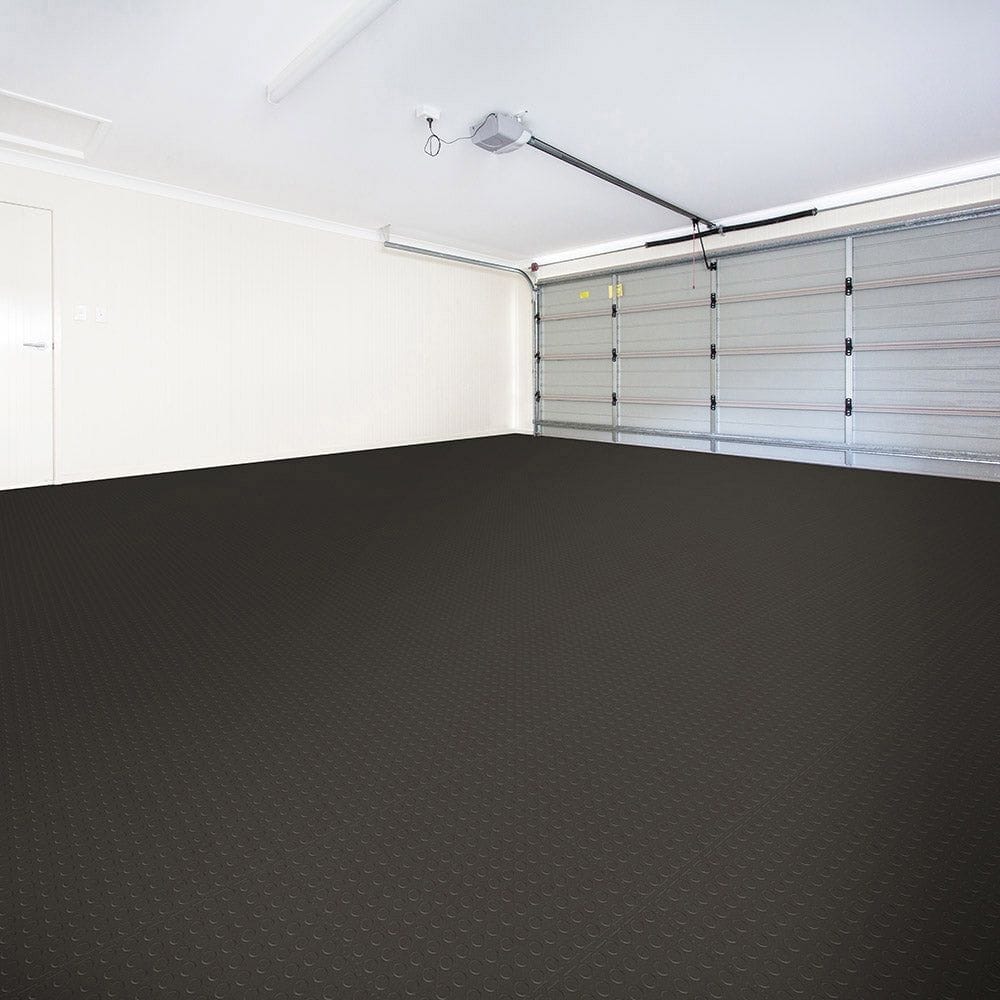 Spacious Garage With White Walls Coin Rubber Floor Tiles By Perfection Tile, A Ceiling Mounted Light Fixture, And A Visible Garage Door