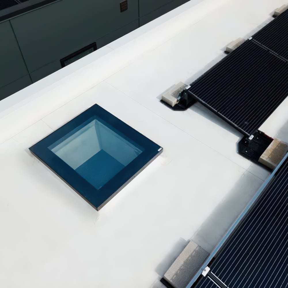 Square Glass Skylight Installed On White Rooftop Beside Solar Panel Array