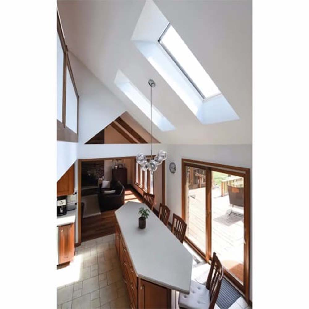 Sunlit Open Plan Dining And Kitchen Area With Two Roof Windows Long Central Island Wooden Chairs And Glass Patio Doors
