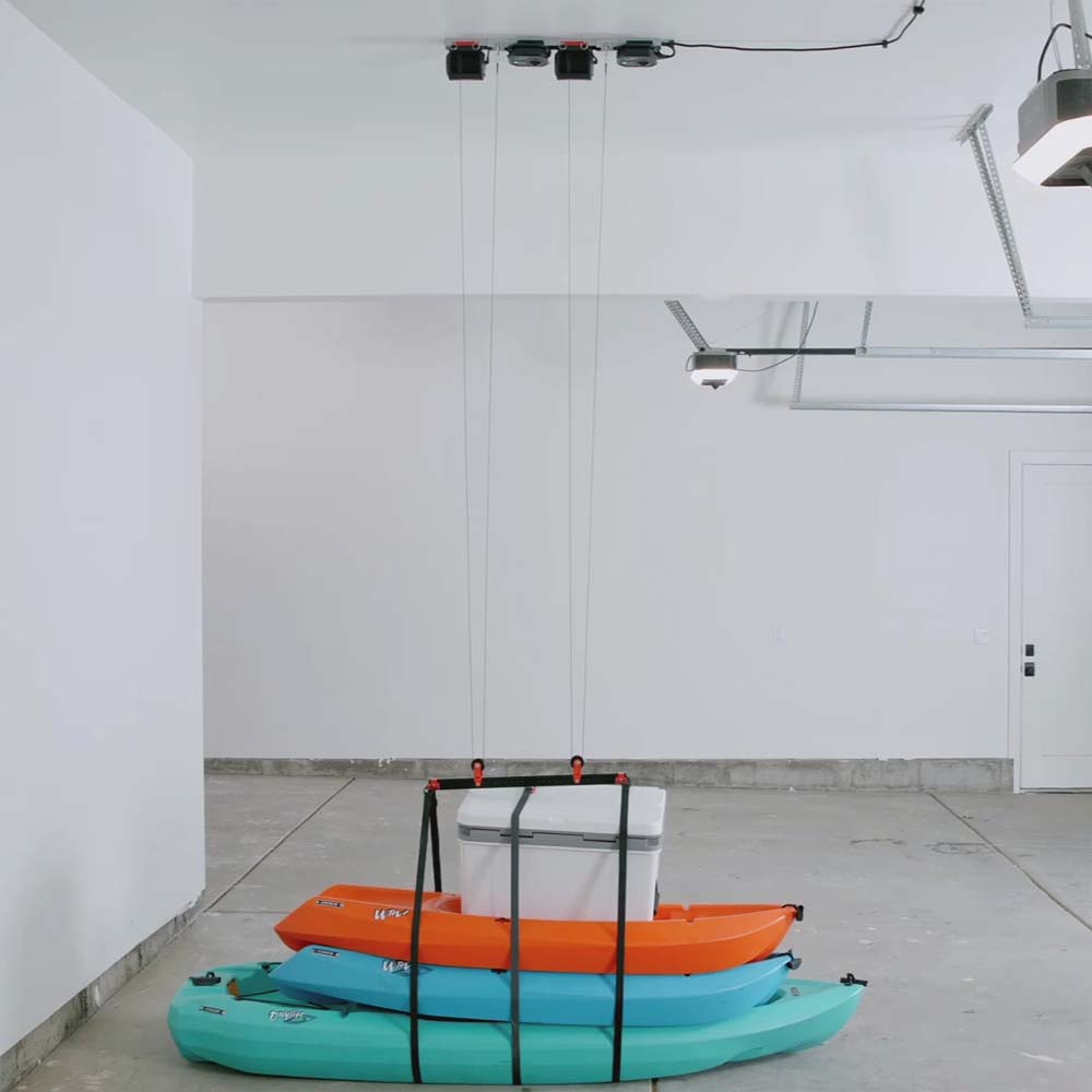 Two Kayaks Are Placed On The Floor Beneath A Suspended Empty Storage Rack By SmarterHome Electric Lifts For Garage Storage