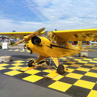 Vintage Biplane With A Propeller And Distinctive Markings Displayed On A Striking Black And Yellow Checkered Race Deck Flooring