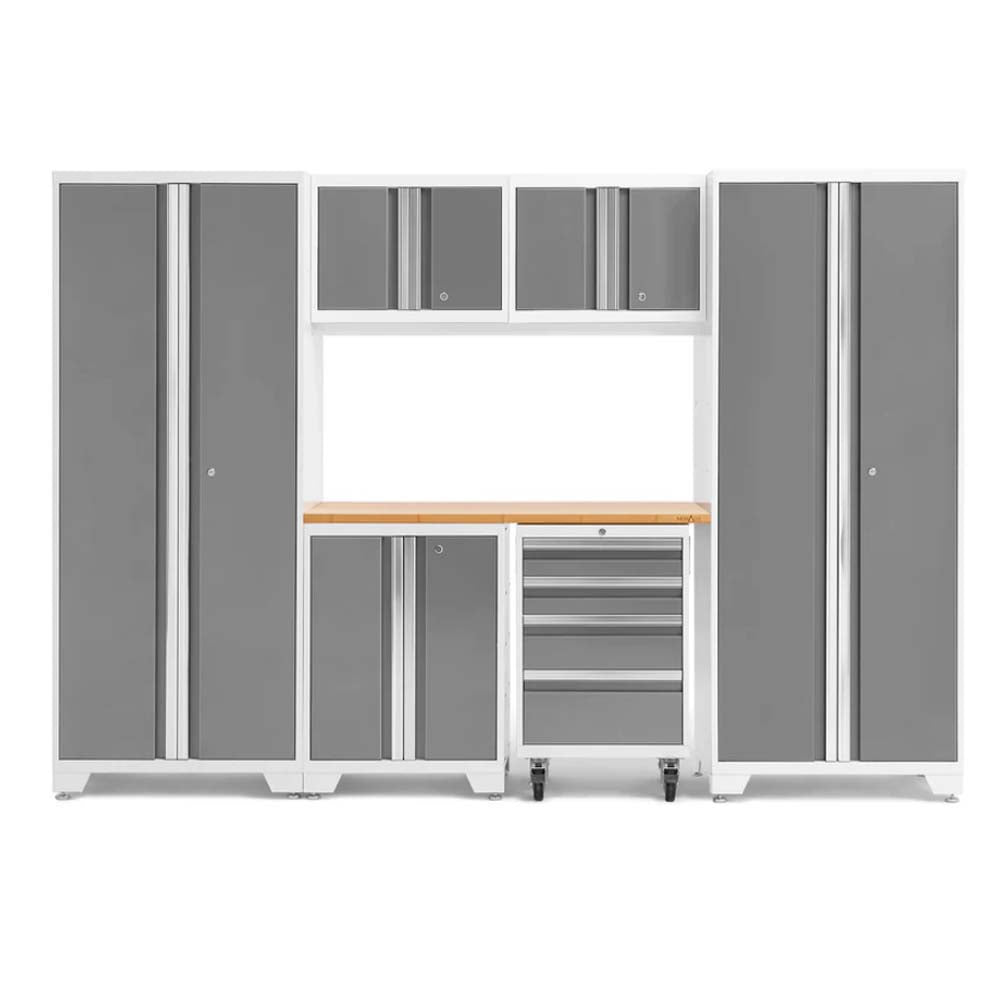 White-Framed Modular Garage Cabinet System With Gray Doors Featuring Two Tall Cabinets Three Upper Units A Central Wood Worktop A Lower Cabinet And A Wheeled Tool Drawer Chest