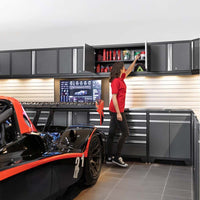 Woman In A Red Shirt Reaches Into An Overhead Cabinet Filled With Automotive Supplies In A Modern Garage