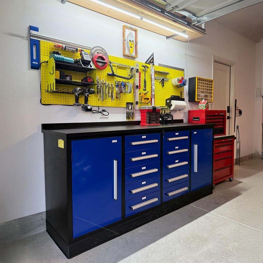 Workbench With Drawers And Cabinets Set Below A Yellow Pegboard Filled With Hanging Tools